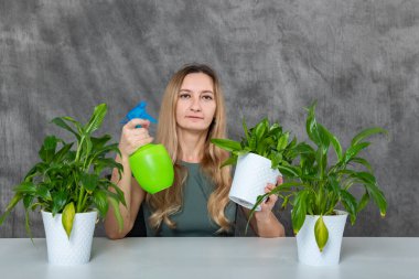 Masada oturan sarı saçlı bir kız, fıskiye kullanarak yemyeşil bitkileri sulamakla meşgul. Sahne, yeşeren yeşilliğe karşı bir özen ve dikkat hissi yayar..