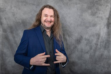 Bu çarpıcı görüntü, keskin mavi takım elbiseli, iş ve moda kavramları için mükemmel bir dizi profesyonel duruş sergileyen, çok yönlü uzun saçlı, çok yönlü bir adamı gösteriyor..