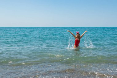Noel Sahil Mutluluğu: Kırmızı Mayo ve Sahildeki Santa Hat. Yüksek kalite fotoğraf