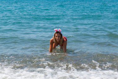 Noel Baba Şapkası Sıçrıyor: Kırmızı Mayolu Kız Dalgalar Yapıyor. Yüksek kalite fotoğraf