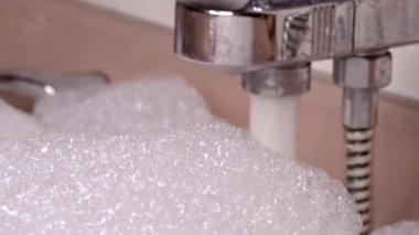 Pembe Küvet ağzına kadar dolu Metalik Musluk Suyla ve Bol köpükle akıyor