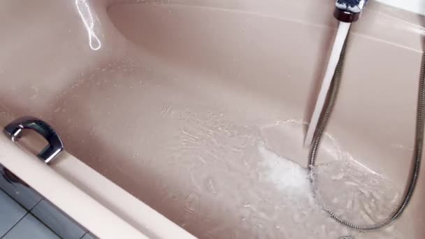 倒入边缘的粉红浴缸 充满水和丰富泡沫的金属水龙头 — 图库视频影像