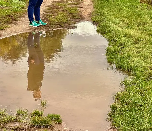 Reflective Puddle on a Country Trail with a Person\'s Silhouette
