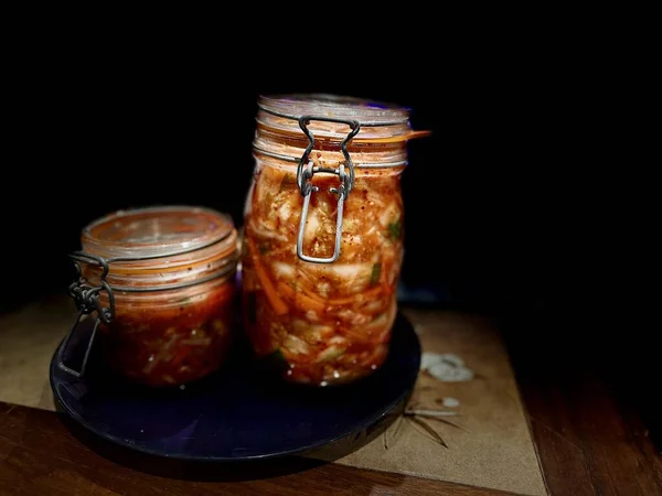 Klemp-üstü kavanozlarda sanatsal Kimchi Koyu Ahşap Yüzeyde dramatik Işıklandırma