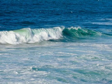 Okyanusun sürekli değişen ruh halinin büyüleyici portresi Zümrüt Dalgaları 'nın Sahile inişi göz kamaştırıcı.