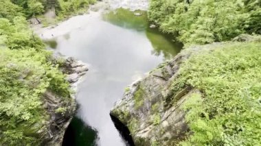 Orrido di Sant 'Anna, Traffiume, Cannobio' daki yemyeşil ormanlarla çevrili sakin bir nehir havuzu bulutlu bir gökyüzü altında, Piemont, İtalya