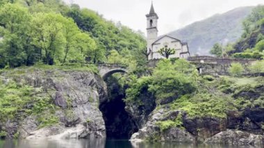 Orrido di Sant 'Anna, Traffiume, Cannobio, Piemont, İtalya' daki dingin yeşil ormanlarla çevrili tarihi bir kilise ve taş kemer köprüsü.