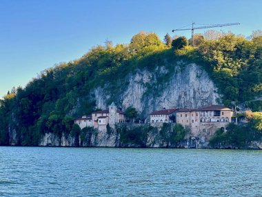 Santa Caterina del Sasso 'nun detaylı manzarası Maggiore Gölü' nün sakin sularına bakan kayalık kayalıklara karşı.