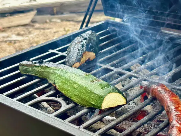 Stock image Grilled Zucchini Cooking on a Charcoal Barbecue Grill with Smoke, Perfect for a Summer Vegetarian BBQ