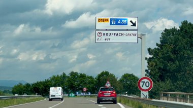 Rouffach, Fransa - 6 Haziran 2024: Otoyol A35 ve D18BIS yol işaretleri şehir merkezine doğru gidiyor. Bulutlu bir günde Haut-Rhin, Alsace 'deki Mulhouse yakınlarında görünür araçlar ve yemyeşil alanlarla...