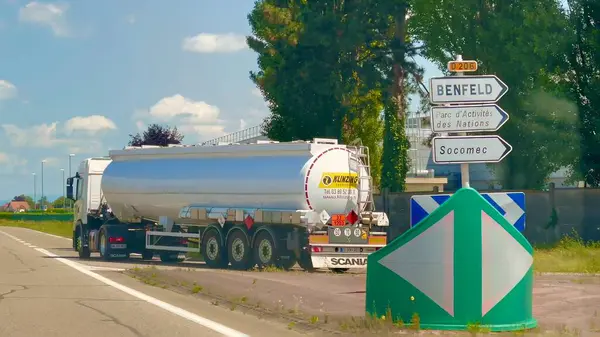 stock image Benfeld, France - June 6 2024 : Tanker truck driving on D206 near Benfeld, Alsace, France, with road signs directing to Benfeld, Parc d'Activites des Nations, and Socomec on a clear day.