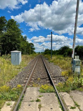 Uzun, Düz Demiryolu Yemyeşil ve Kabarık Bulutlu Mavi Gökyüzü 'nün ortasındaki Mesafeye Uzanıyor