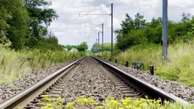 Uzun, Düz Demiryolu Yemyeşil ve Kabarık Bulutlu Mavi Gökyüzü 'nün ortasındaki Mesafeye Uzanıyor