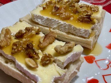 Lezzetli Fransız peyniri taze baget dilimlenmiş gevrek ceviz ve tatlı bal ile süslenmiş kırmızı kalplerle dekoratif bir tabakta servis edilmiş