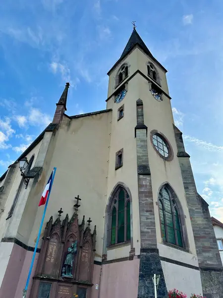 Lautenbach-Zell, Fransa - 21 Ağustos 2024: Sengern 'deki Saint-Nicolas Kilisesi, Sahne Alsas Mimarisi, Kule Saat Kulesi, Fransız Bayrağı ve Sunset' teki Picturesque Surround
