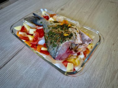 Tüm Baharatlı Deniz Balığı Taze sebzelerle pişmiş Tahta tezgahta Domatesler, Patatesler ve Soğanlar dahil, Ev Mutfağında Kızarmaya Hazır