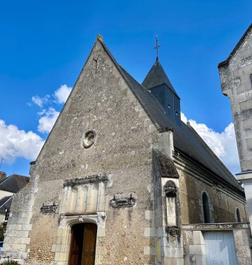 Chenonceaux, Fransa - 19 Eylül 2024: Chenonceaux 'daki Saint-Jean-Baptiste Kilisesi' nin dışı, yıpranmış kaya perçemi, dik çatı ve açık mavi gökyüzü altında kırsal mimari özellikler