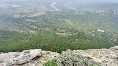 Pic Saint-Loup 'tan Hortus Dağı' na tepeden bakan hava manzarası, Valflauns 'ın Verdant Ovaları ve Güney Fransa' da dramatik bulutlu bir gökyüzü altında tarihi manzaralar kalesi.