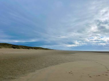 Berck Sahili ve Authie Körfezi 'nin geniş ve huzurlu manzarası dramatik bulutlu bir gökyüzü altında, geniş kumlu plajlar, kayan kumullar, uzak sahil kasabası Fort-Mahon, Fransa' nın kuzey kıyı şeridi.