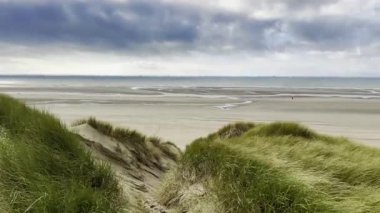 Authie Körfezi 'ndeki görkemli kıyı manzarası. Rüzgârlı kum tepecikleri ile kaplıydı. Geniş bir kumsal, gelgit havuzları ve dinamik bulutlu bir gökyüzü altında açık deniz.