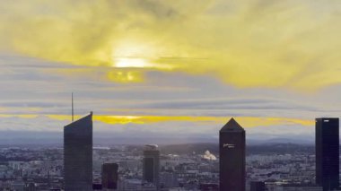 Lyon, Fransa - 23 Mart 2025: Modern gökdelenlerin ve tarihi çatıların siluetleri ile Lyon şehrinin üzerinde geniş panoramik gündoğumu manzarası, bulutlarla dolu bir gökyüzünün altında Fourviere tepesinden görüldü.