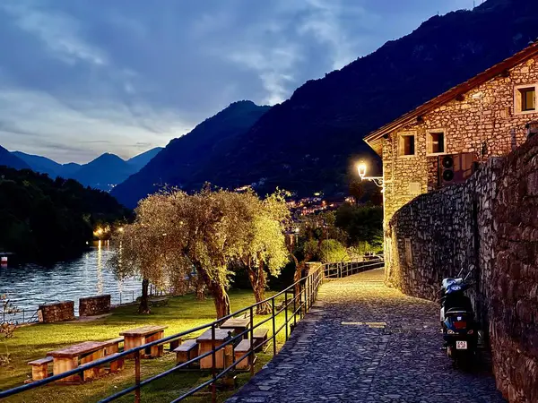 Lenno, İtalya - 2 Mayıs 2025: Lenno ve Ossuccio 'da gece manzarası, kaldırımlı sokaklar, taş evler, zeytin ağaçları, göl kenarındaki patikalar ve geleneksel göl köylerinin sessiz cazibesini çağrıştıran sokak lambaları
