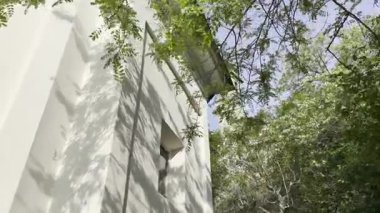 İtalya, Como Gölü, Ossuccio 'daki Madonna del Soccorso Sığınağı' nın altından, taştan duvarlar, çan kulesi ve parlak mavi bir yay altında yemyeşil bir gökyüzü.