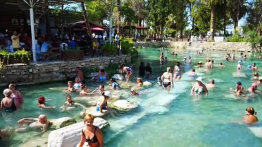Pamukale, Türkiye - 14 Eylül 2022: Pamukkale, Türkiye 'de antik havuz Cleopatras Hamamı' nın tadını çıkaran turistler. Yüksek kalite 4k görüntü