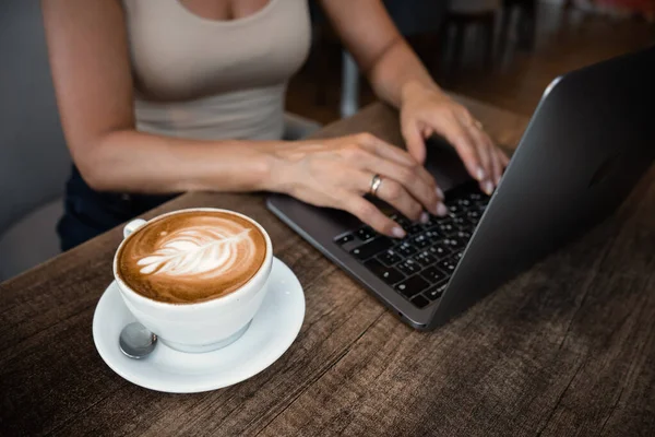 stock image Unrecognizable woman sits at table in cafe with cup of coffee and working in laptop. High quality photo