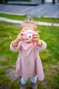 Yürüyen Kız, Summer Park 'ta Pembe Dijital Çocuklar Kamerasıyla Fotoğraf Çekiyor. Yüksek kalite fotoğraf
