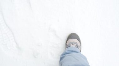 Feet in winter shoes walk on snow-white snow, top view. High quality 4k footage