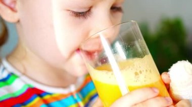 Little girl drinking fresh juice sitting on table in home kitchen. High quality 4k footage