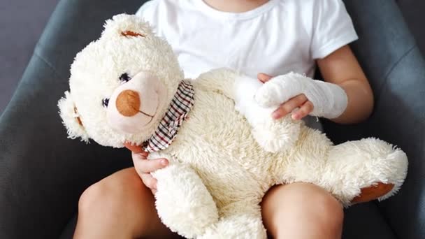 Kleines Mädchen Mit Gebrochenem Finger Hält Teddybär Mit Bandagierter Pfote — Stockvideo