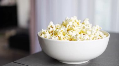 Little girl is eating popcorn in home kitchen. Focus on hand taking popcorn. High quality 4k footage