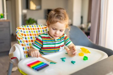 Little girl plays with multi-colored plasticine, creates different shapes. High quality photo