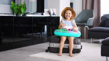 Little girl with suitcase baggage luggage and inflatable life buoy ready to go for traveling on vacation. High quality 4k footage