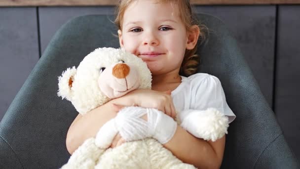 Liten Flicka Med Brutet Finger Håller Teddybjörn Med Bandagerad Tass — Stockvideo