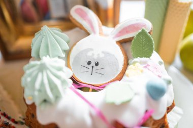 Easter cake decorated gingerbread in the form of a rabbit on table in home kitchen. Church icons and candle on background. Orthodox religion theme. High quality photo