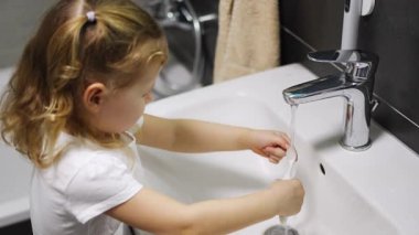 Happy toddler girl washing toothbrush after brushing teeth in the bath. High quality 4k footage