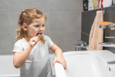 Happy toddler girl brushing teeth in the bath. High quality photo