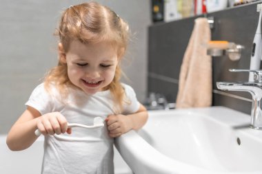 Happy toddler girl brushing teeth in the bath. High quality photo