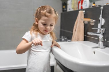 Happy toddler girl brushing teeth in the bath. High quality photo