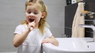 Happy toddler girl brushing teeth in the bath. High quality 4k footage