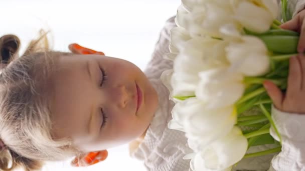 小女孩坐在窗边 手里拿着郁金香花束 快乐的孩子 在室内 母亲节 情人节或生日的概念 高质量的4K镜头 — 图库视频影像