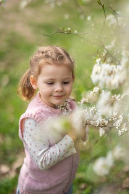 Prag Parkı 'nda çiçek açan elma ağacının yanında güzel ve güneşli bir bahar gününün tadını çıkaran küçük bir kız. Yüksek kalite fotoğraf
