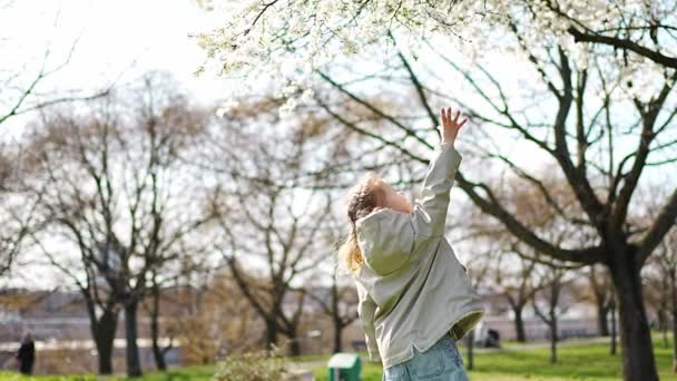 ヨーロッパのプラハの春の公園で木の下にジャンプする幸せな女の子 高品質4K映像 — ストック動画