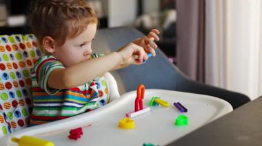 Little girl plays with multi-colored plasticine, creates different shapes. High quality 4k footage