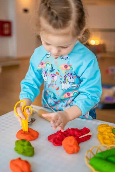 A little girl playing with plasticine. Sensory development and experiences, themed activities with children, fine motor skills development. High quality photo