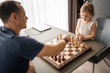 Baba küçük kızına evde mutfakta satranç oynamayı öğretiyor. Erken çocukluk gelişimi ve eğitim kavramı. Aile eğlencesi, iletişim ve eğlence. Yüksek kalite fotoğraf