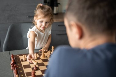 Küçük kız babasıyla ev mutfağında satranç oynuyor. Erken çocukluk gelişimi ve eğitim kavramı. Aile eğlencesi, iletişim ve eğlence. Yüksek kalite fotoğraf